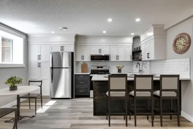 Kitchen and dining space in legal Calgary basement suite featuring large window, two-tone custom cabinetry, pantry, and eating bar.
