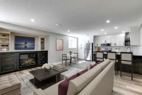 Living, kitchen and dining area of legal Calgary basement suite featuring custom cabinetry and an electric fireplace with built-ins.