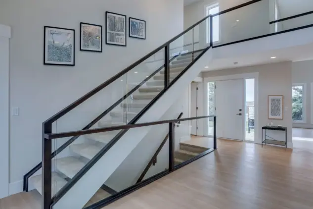 Stunning modern glass railings on staircase off foyer in renovated Rocky View County home