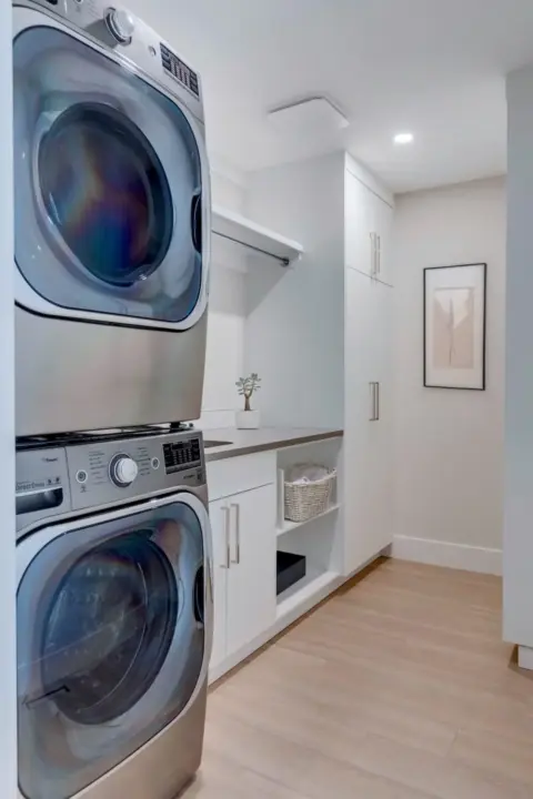 Laundry room with custom white flat panel cabinetry and shelving in renovated Rocky View County home