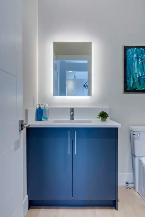 Rich blue, flat panel vanity with with white quartz countertop in powder room of renovated Rocky View County home