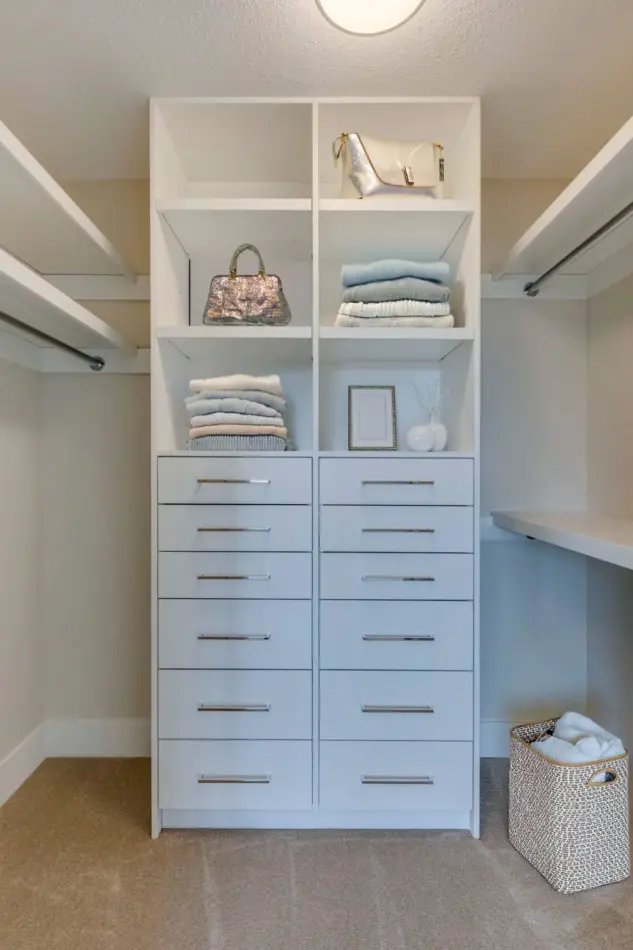 Walk-in closet with white custom shelving and drawers in renovated Rocky View County home