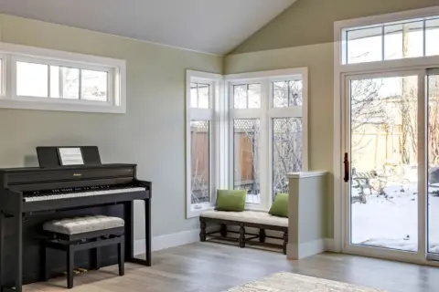 Window-filled corner of rear Calgary home addition looking out to backyard