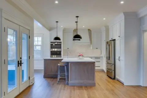 White inset Shaker cabinetry with (type of wood) stained, L-shaped island and (descriptor) quartz countertops