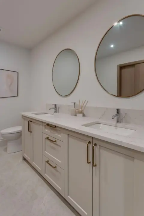Ensuite bathroom in third-floor townhome suite with dual sinks, quartz countertop, and spacious custom cabinetry
