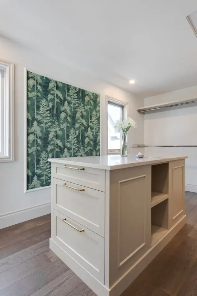 Dream walk-in closet with central island, ample storage, and wallpaper accent