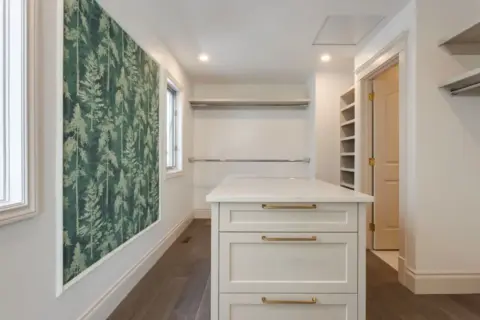 Dream walk-in closet with central island, ample storage, and wallpaper accent