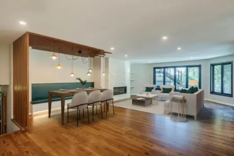 Kitchen dining nook and family room in Rocky View County home featuring unique wood slat feature at dining nook and stone clad fireplace in family room.