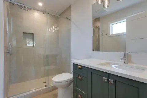 Bathroom with bold green custom cabinetry, white quartz countertops and big shower