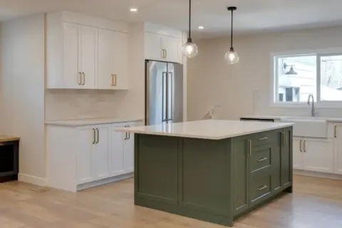Kitchen in remodeled Wildwood Calgary home with bold green island topped in white quartz, white Shaker custom cabinetry with brushed gold hardware and white farmhouse sink