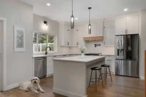 Completed renovated kitchen in Cranston home with two-tone cabinetry, quartz countertops, a large central island, and adjacent butler's pantry and tech station