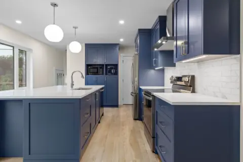 Stunning kitchen with vibrant blue custom cabinetry, sleek quartz countertops and a spacious island