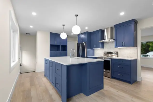 Stunning kitchen with vibrant blue custom cabinetry, sleek quartz countertops and a spacious island