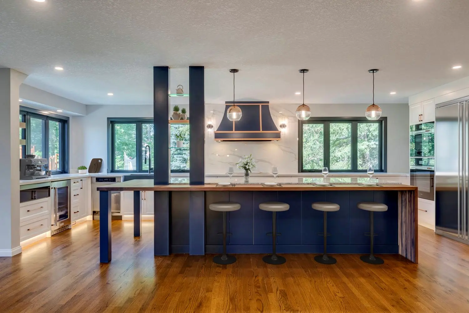 Fully custom kitchen in Rocky View County home renovated by Melanson Homes featuring rich blue island, white Shaker custom cabinetry and custom blue and copper accents on lighting and hood fan cover.